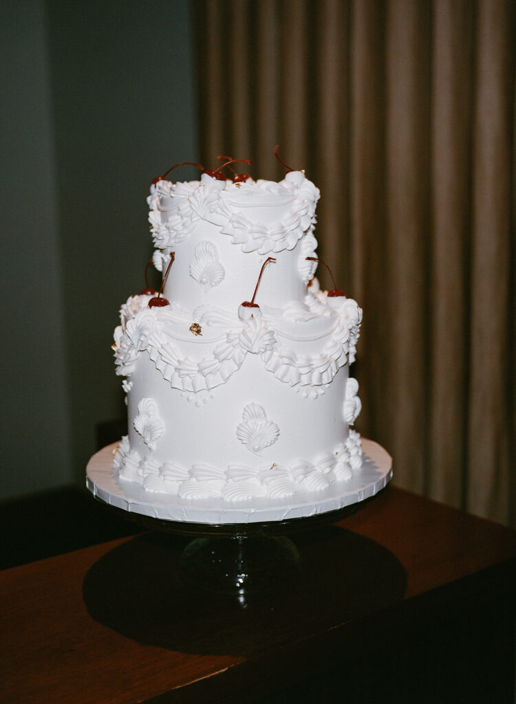 White wedding cake with decorative icing and cherries
