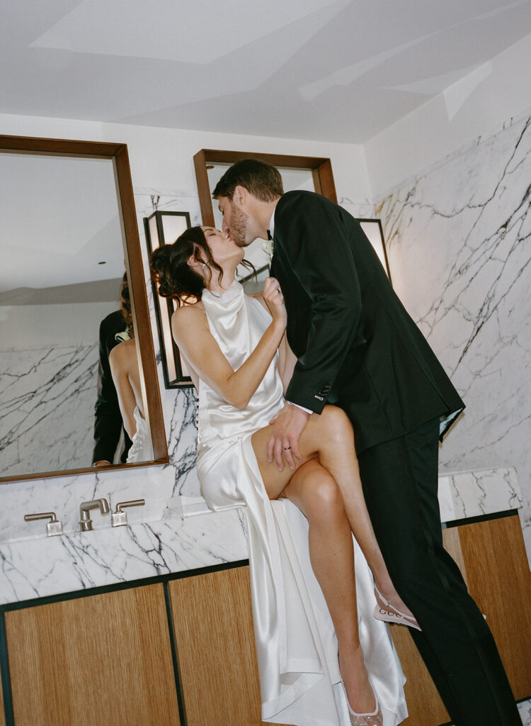 Bride and groom stealing a moment alone in marble bathroom