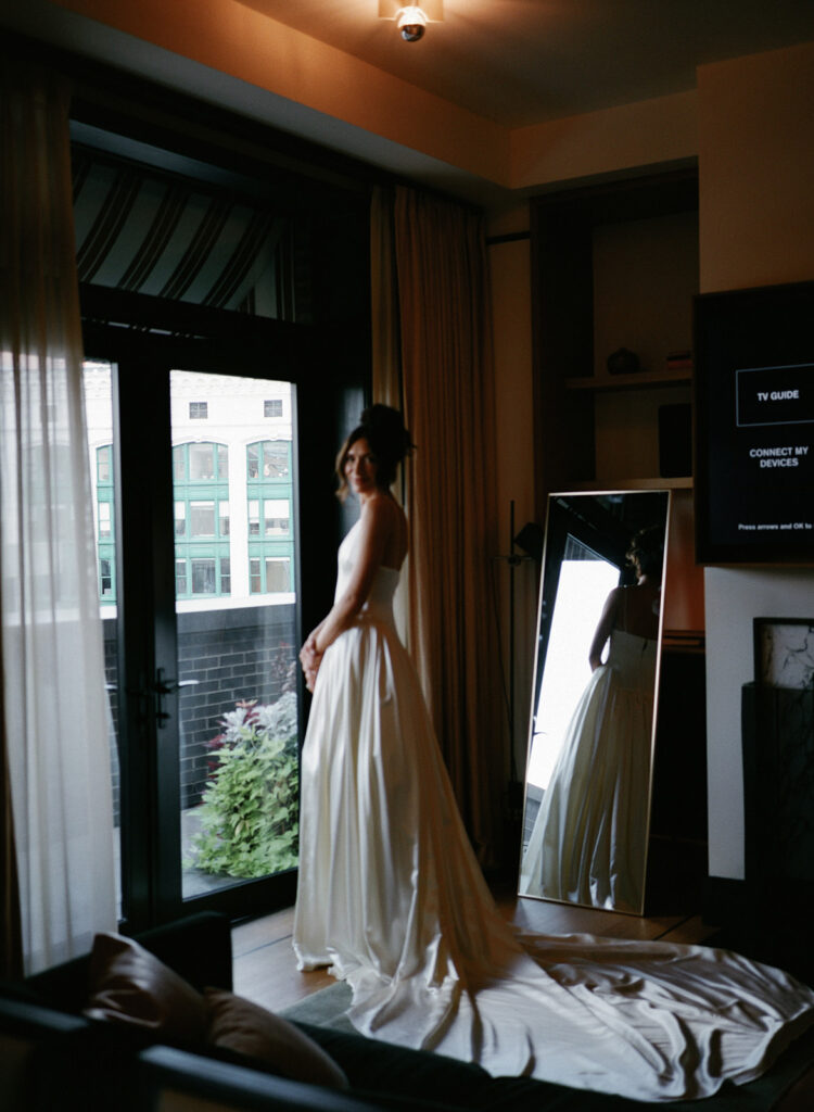 Bride with her gown's train spread out in front of window
