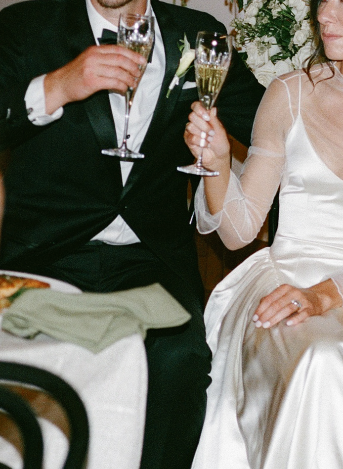Artistic cropped wedding photography shot of bride and groom cheersing