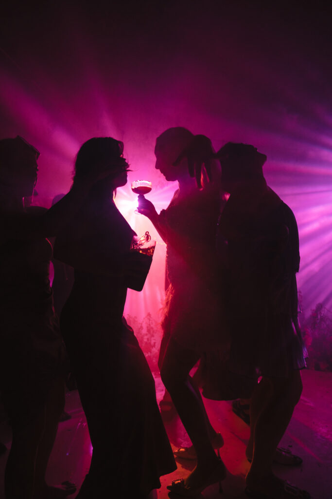 Guests at Thailand destination wedding dancing while backlit by pink light
