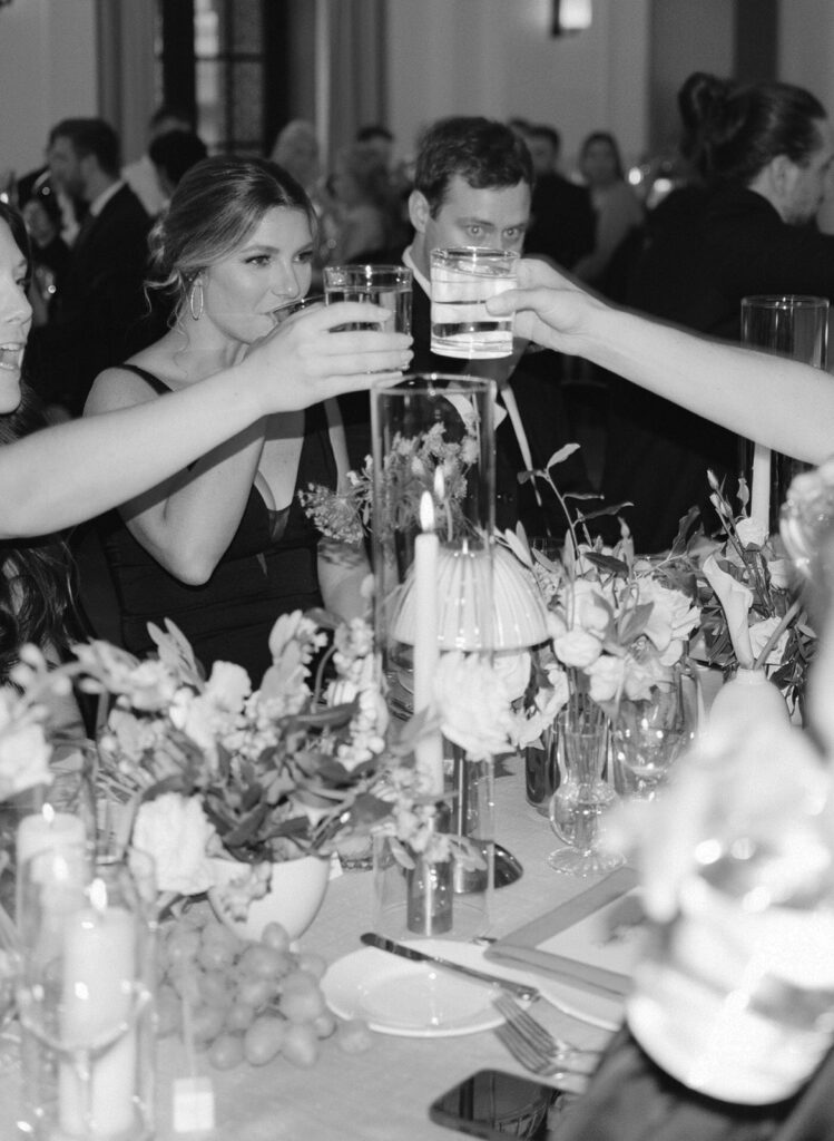 Black and white candid of chic Detroit wedding guests cheersing