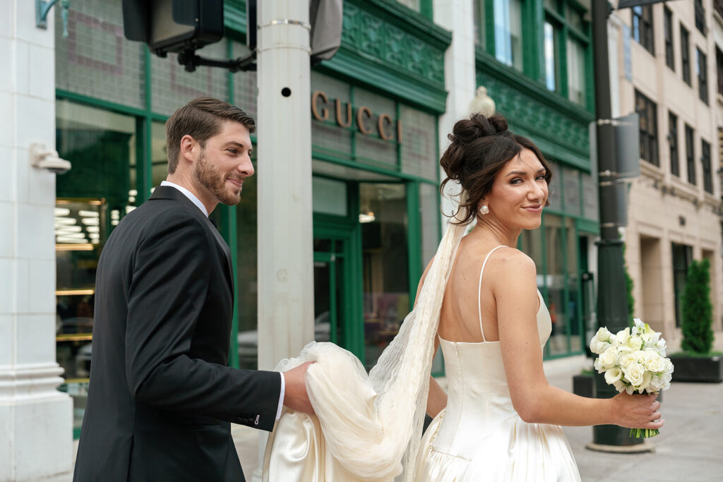 Bride and groom walking down Detroit sidewalk in front of Gucci store