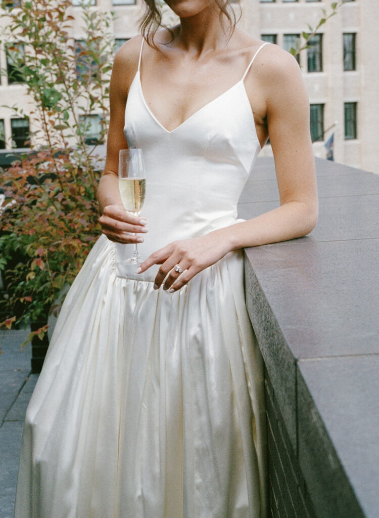 Editorial photo of bride holding champagne from the neck down