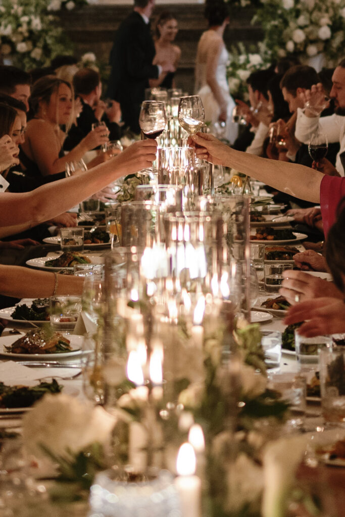 Chic Detroit wedding guests toasting at long candle-lit table