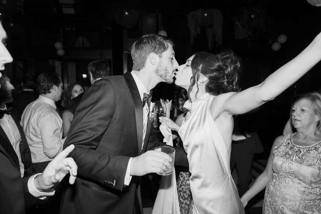 Candid photo of bride and groom kissing on the dancefloor