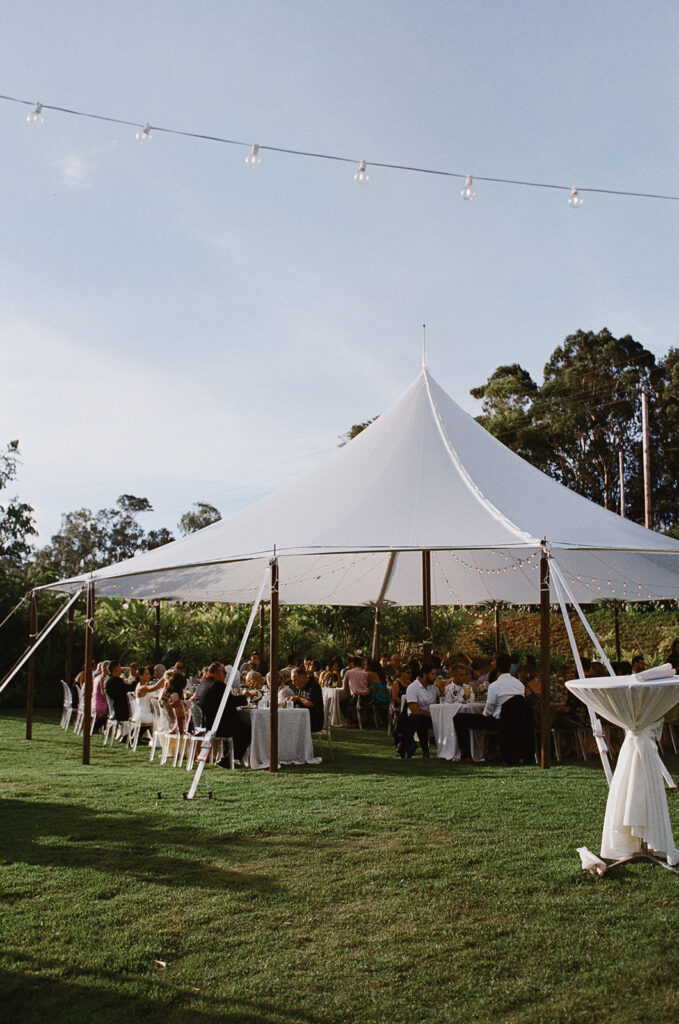 Oahu wedding guests under a white tented canopy