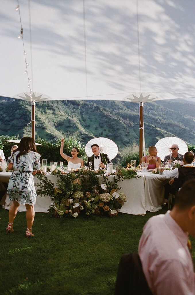 Bride and groom sitting at the head table during Oahu wedding reception