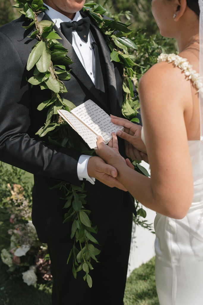 Close up of bride and groom holding hands while exchanging vows