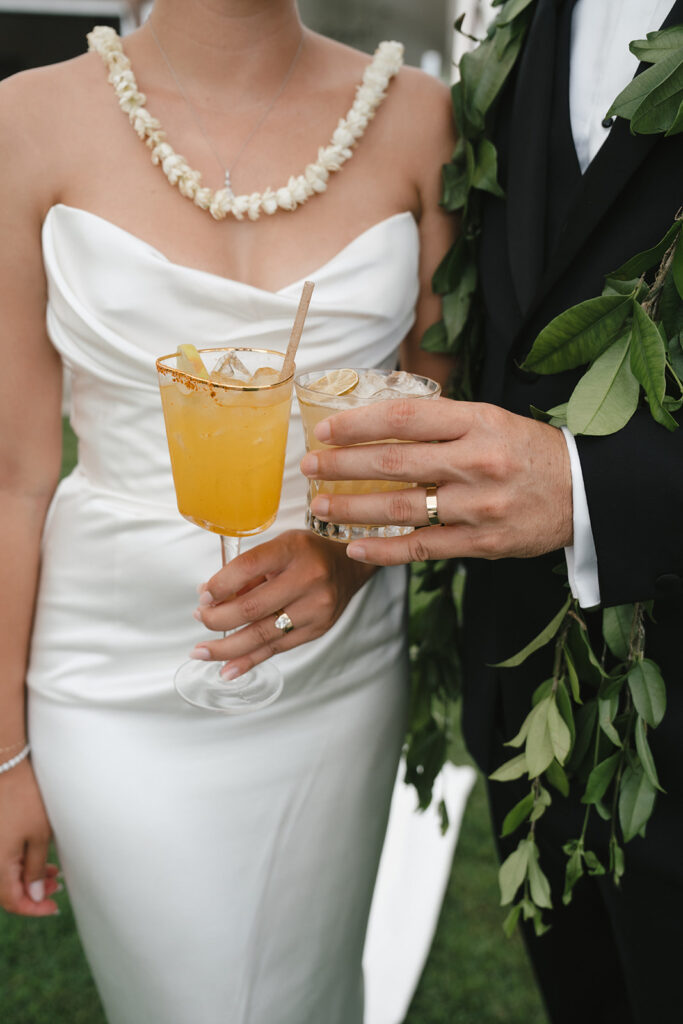 Close up shot of bride and groom's hands holding cocktails