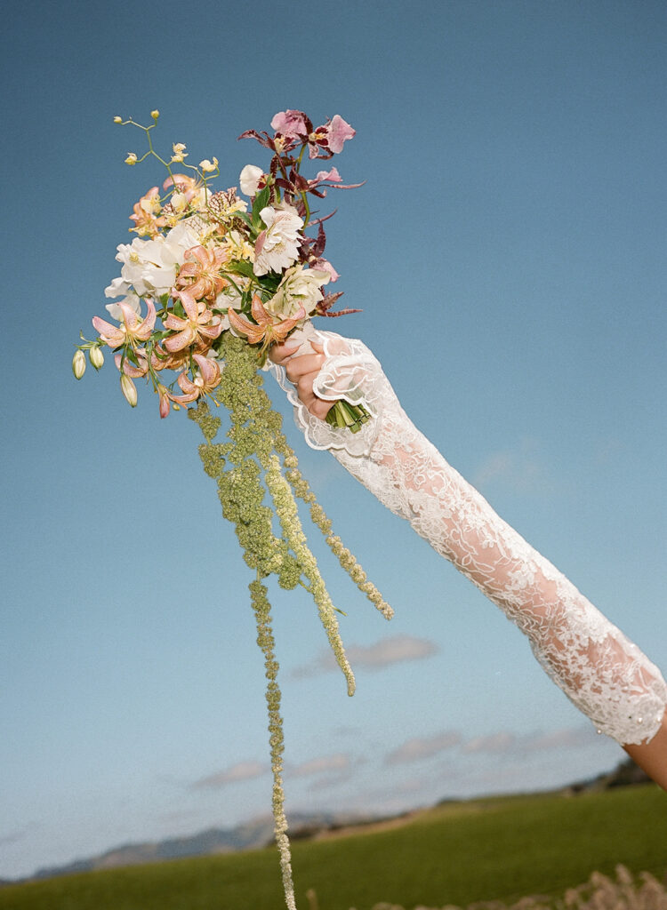 Editorial photo of bride with lace sleeve holding bridal bouquet