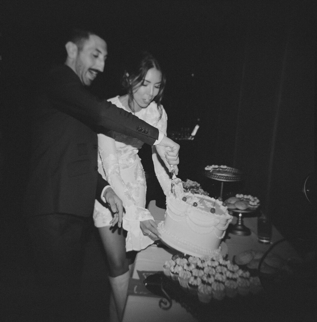 Candid photo of bride and groom cutting cake