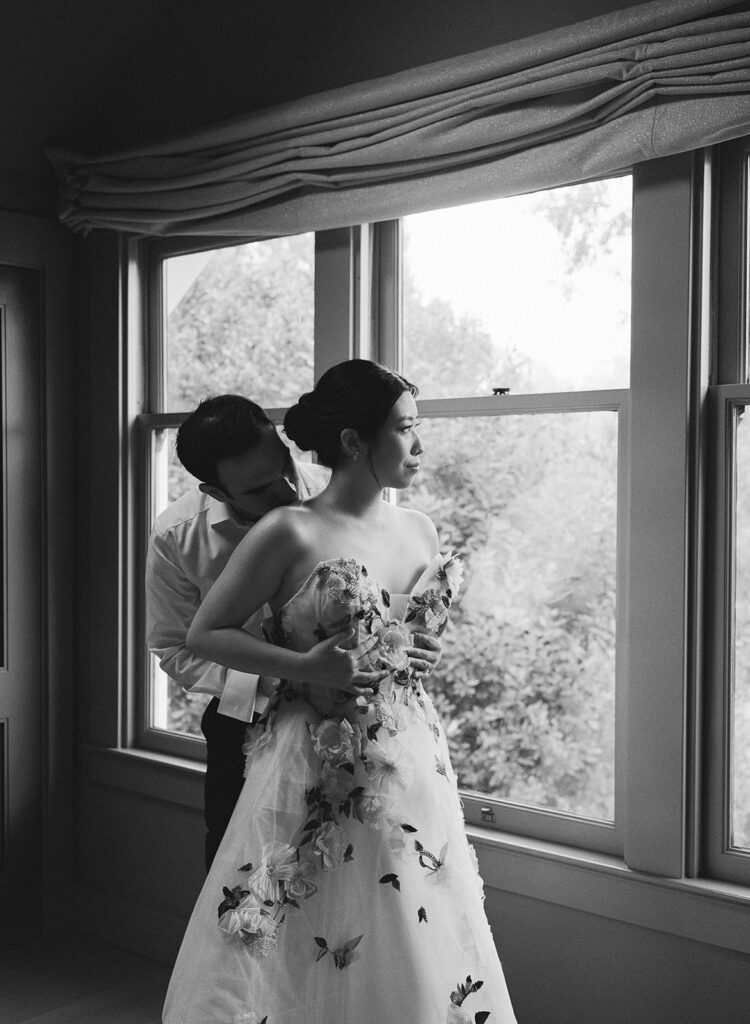 Intimate shot of groom zipping bride into her wedding gown