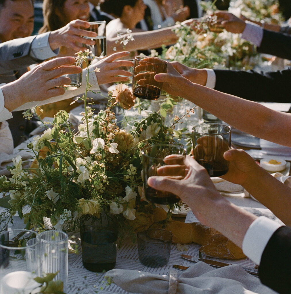 Elevated Sonoma, CA, wedding guests cheersing over floral centerpiece